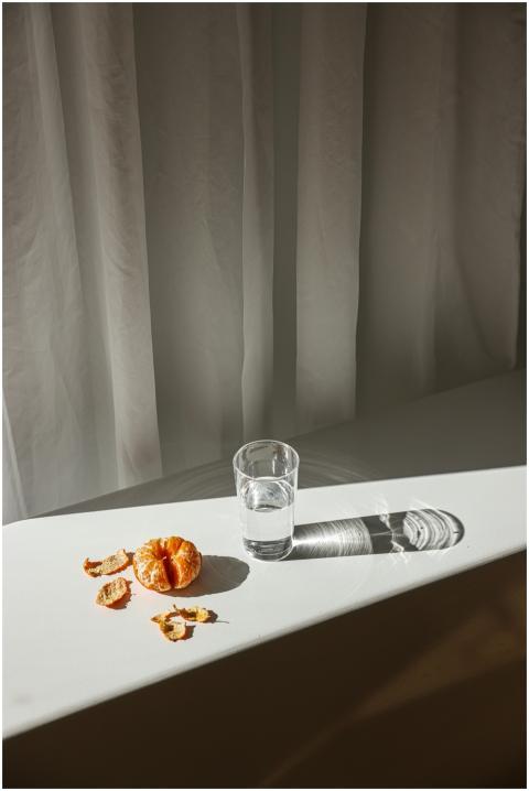 A minimalist scene with a peeled orange and a glas