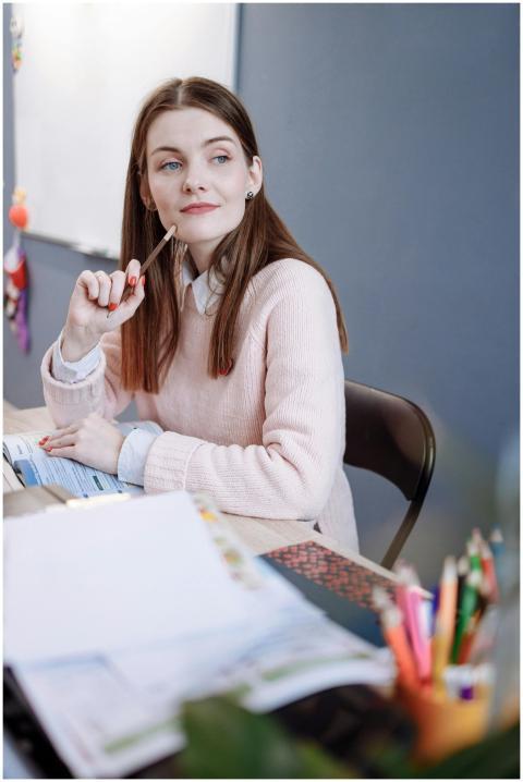 A woman in a pink sweater sits thoughtfully in a c