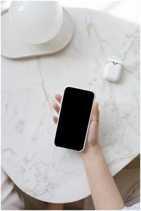 A person holding a smartphone on a marble table wi