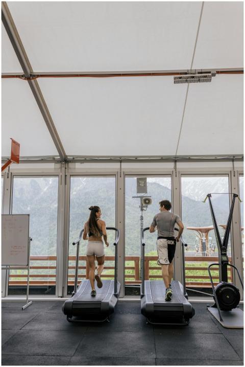 Back view of a couple running on treadmills in a g
