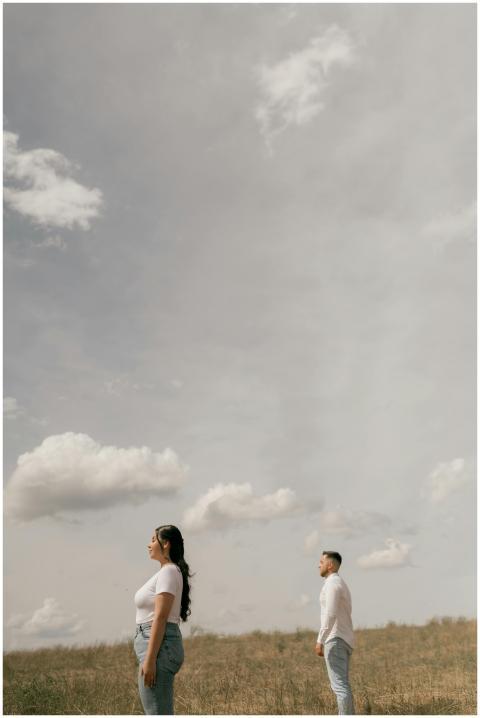 A contemplative couple stands under a vast sky in