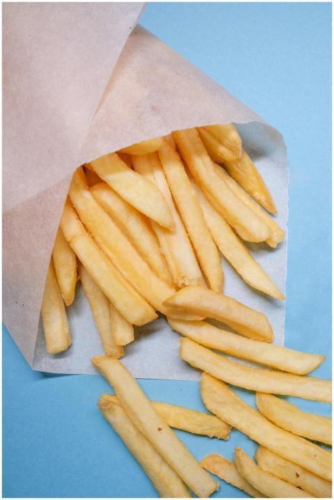 Freshly fried French fries spilling from paper on