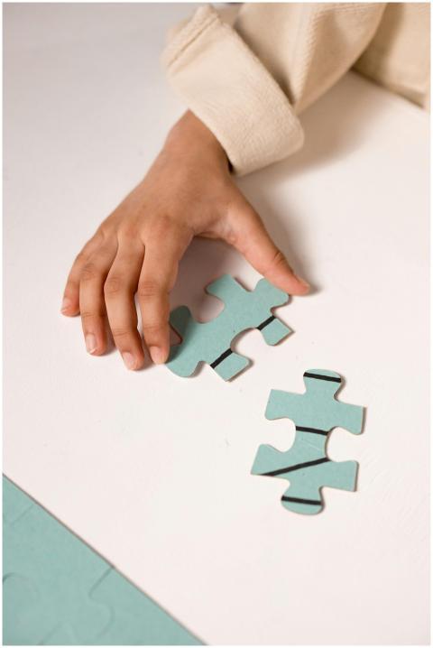 A child's hand in focus, solving a pastel blue puz