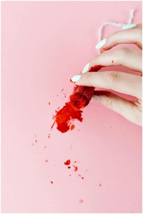 Close-up of a hand holding a red-stained tampon ov