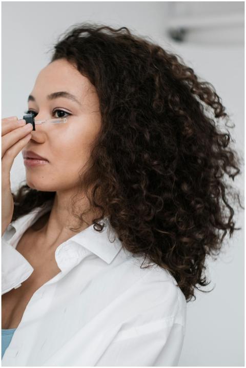 Woman with curly hair applying skincare oil to her