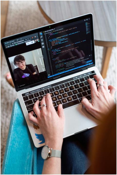 Person coding on a laptop during a video conferenc