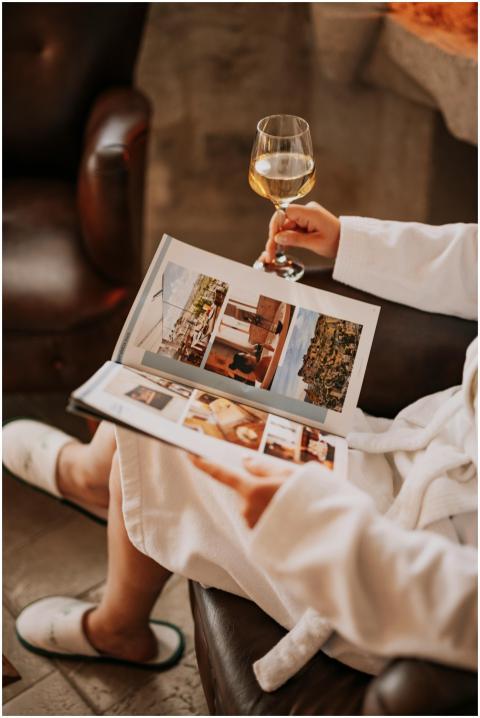 Woman relaxing indoors with wine and a photo album
