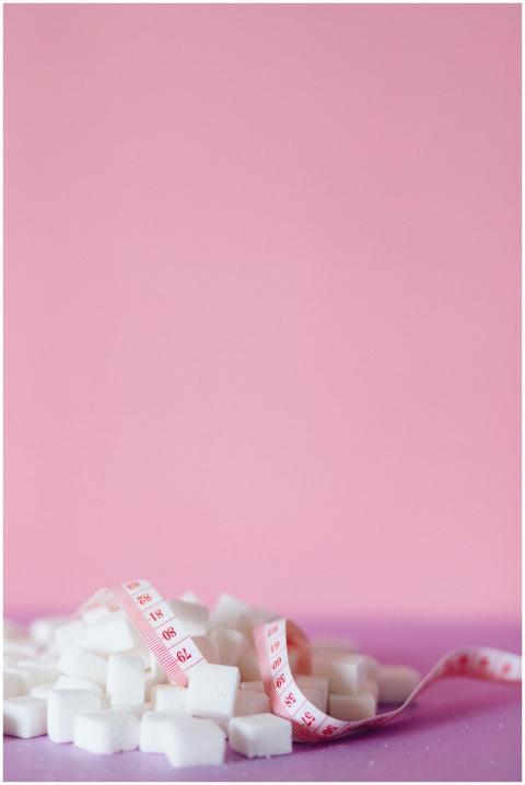 Sugar cubes with measuring tape on pink and purple