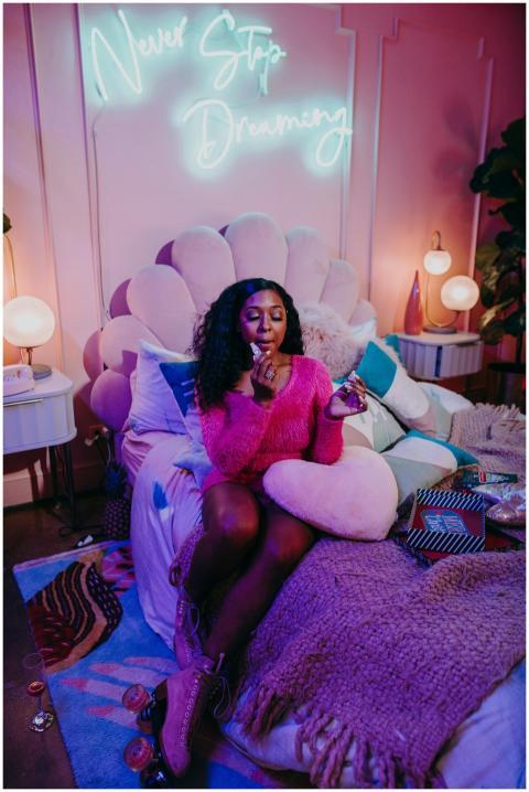 Teen girl in a cozy, stylish bedroom with neon 'Ne