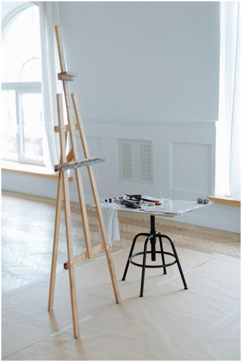 Bright art studio featuring a wooden easel and pai