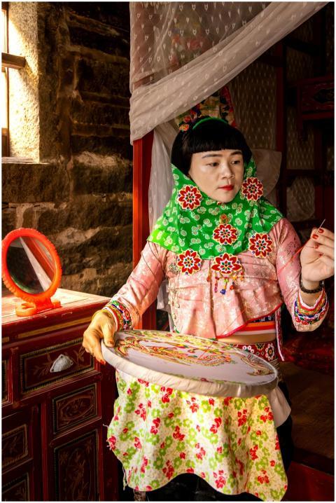 Woman crafting embroidery in traditional attire wi