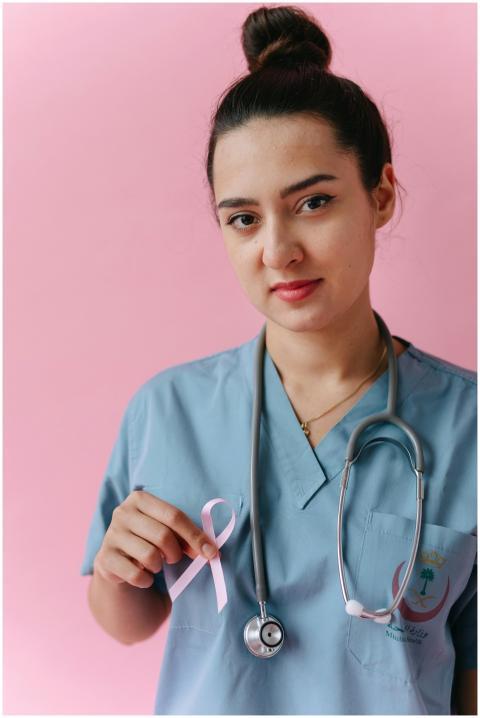 Female doctor in scrubs with pink ribbon for breas
