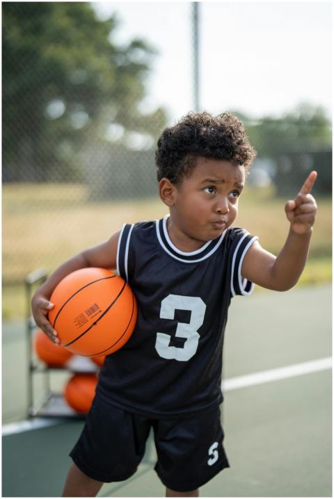 A young boy holding a basketball on an outdoor cou