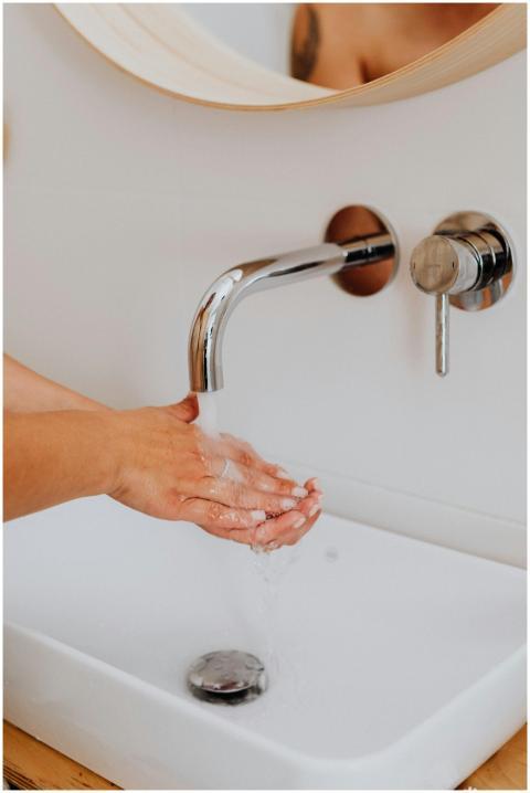 A close-up of hands being washed in a modern bathr