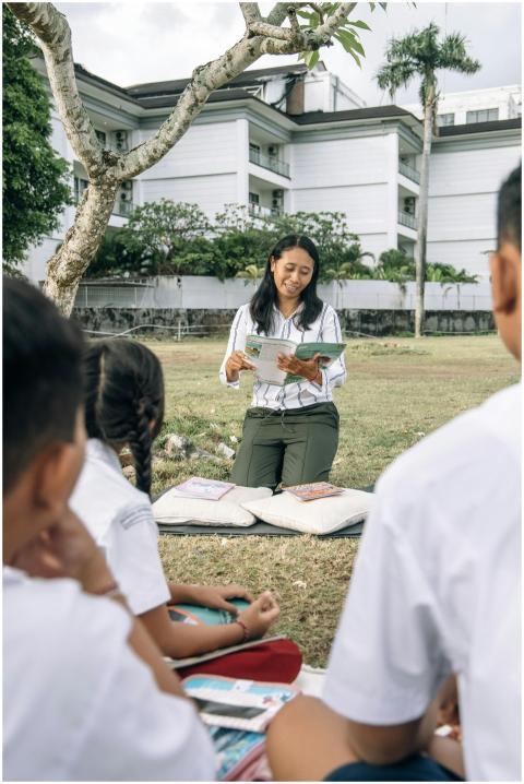 Teacher reading to children outdoors in a sunny se