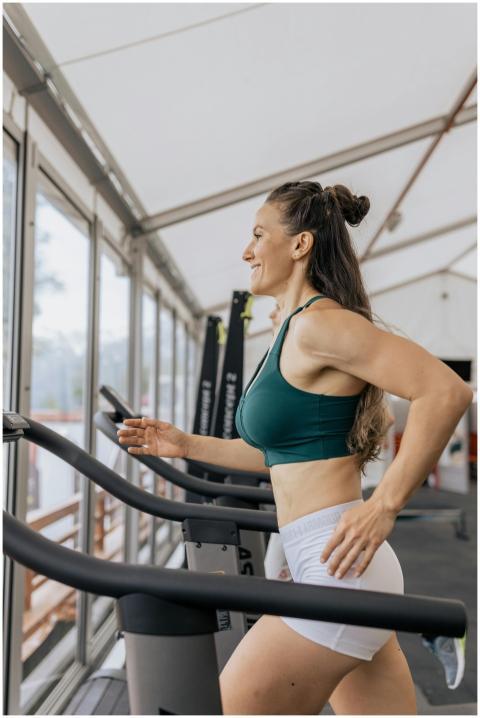 Fit woman jogging on treadmill in an airy gym, foc