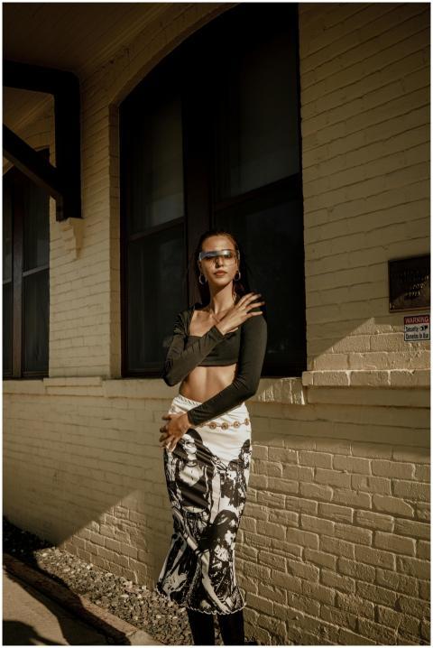Fashionable woman poses against brick wall in urba