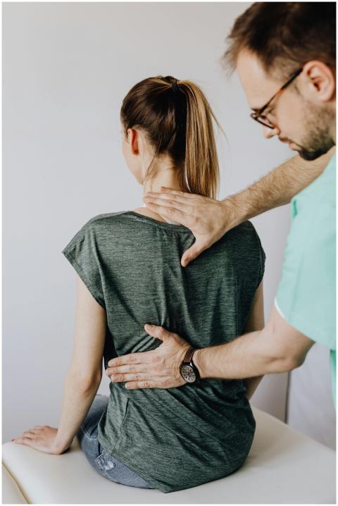 A chiropractor examines a patient's spine in a cli
