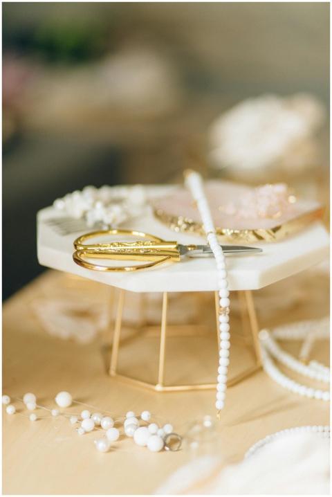 A close-up of gold scissors and white beads on a m