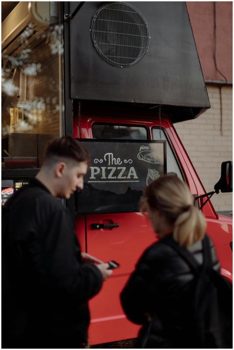 Young couple ordering pizza from a vibrant red foo