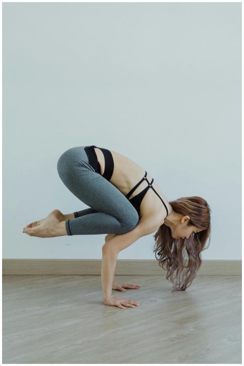 Woman balancing in yoga crow pose indoors. Perfect