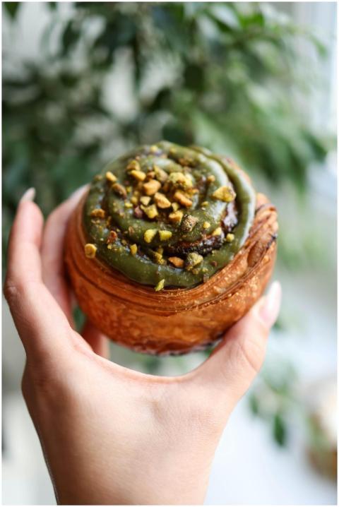 Delicious pistachio-topped cinnamon bun held outdo