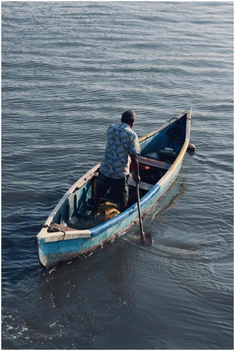 Man Navigates Wooden Boat