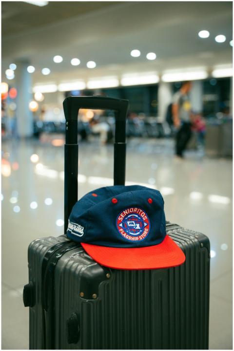 A trendy cap resting on a suitcase handle at a mod