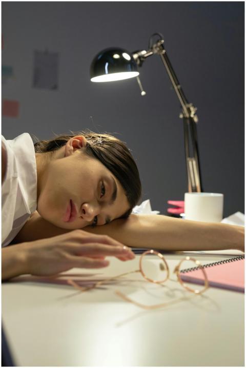 Tired woman resting head on desk with a lamp, repr