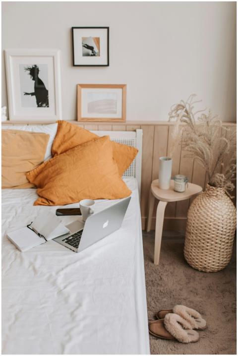 A stylish bedroom setup featuring a laptop, orange