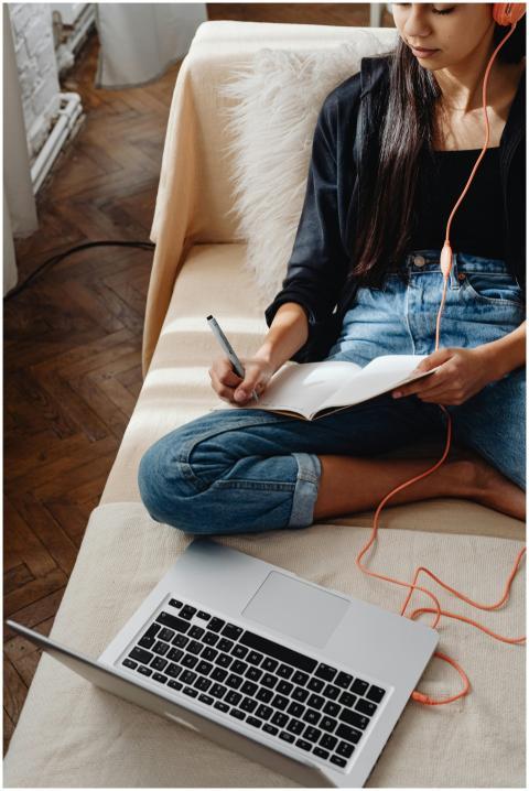 Young woman studying at home on a couch with a lap