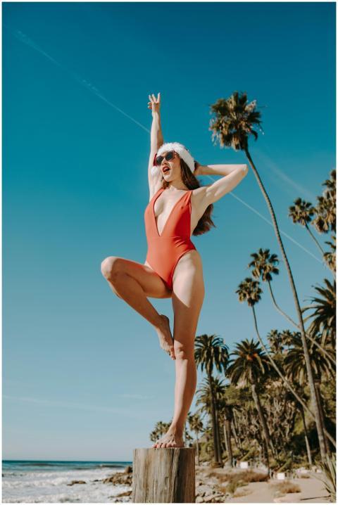 A young woman in a red swimsuit and Santa hat stri