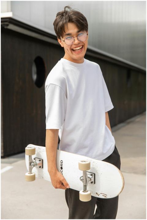 Happy young man with glasses holding a skateboard