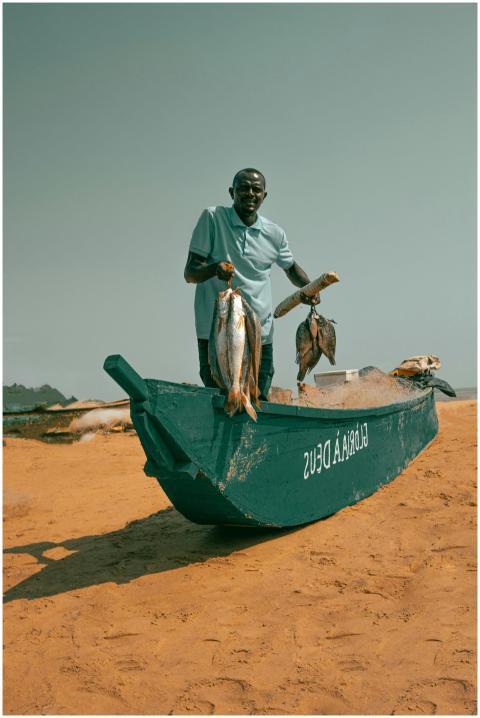 A fisherman proudly displays his catch on a sandy