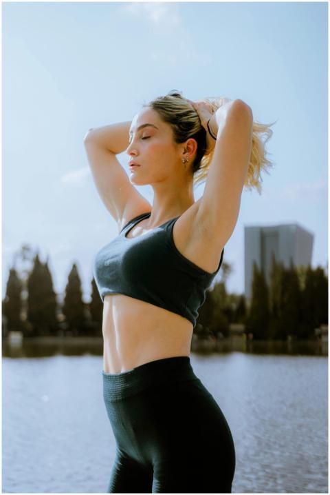 A woman in sports clothing exercises by a lake in