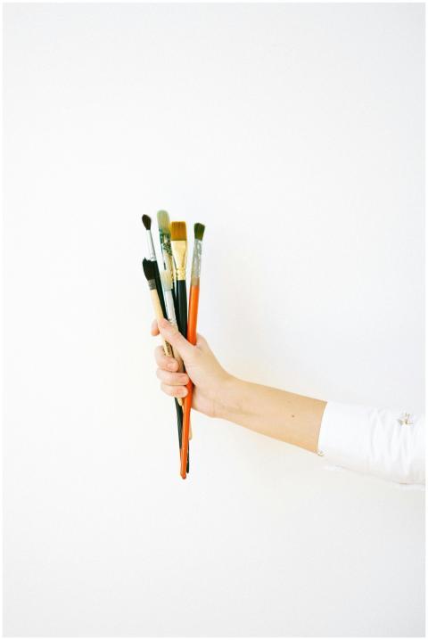 A hand holds a variety of paint brushes against a