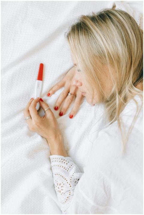 A woman lying on a bed looking at a positive pregn