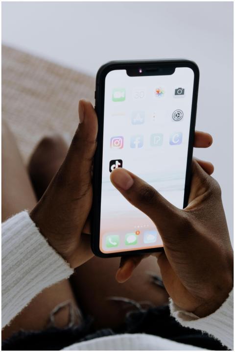 Hands holding a smartphone showing various apps in