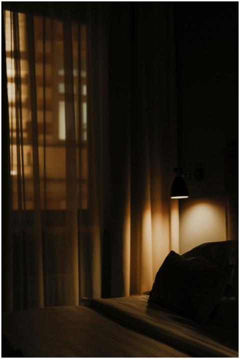 Dark, ambient hotel room with bed and soft lightin