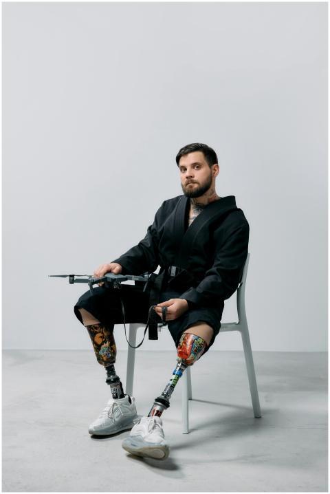 A bearded man with prosthetic legs holding a drone