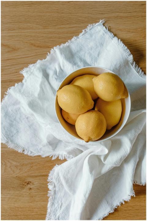 A bowl of vibrant lemons placed on a wooden table