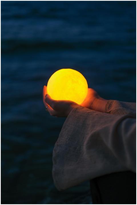 A glowing orb held by a hand against a dark water