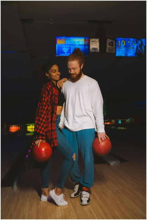 A couple shares a moment at a bowling alley, each