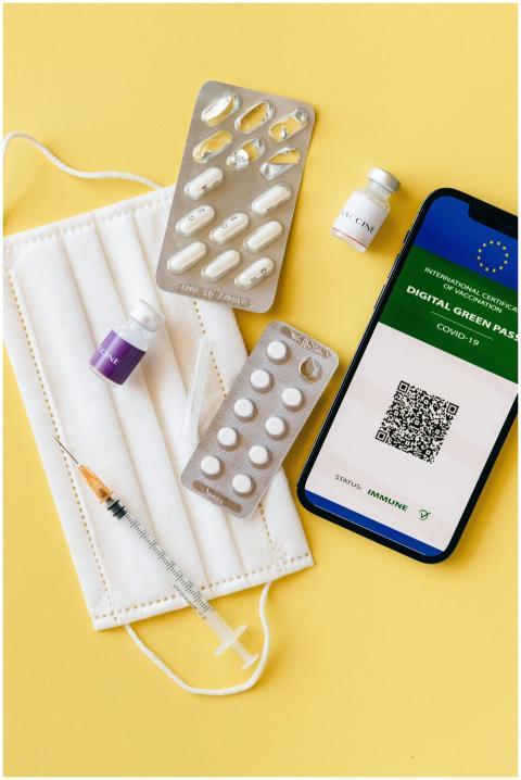 Flat lay of pandemic essentials: mask, vaccine via