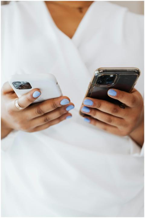 Close-up of hands with blue nails holding two smar