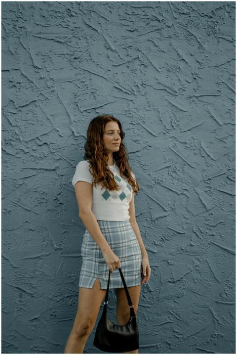 A fashionable woman stands confidently against a b