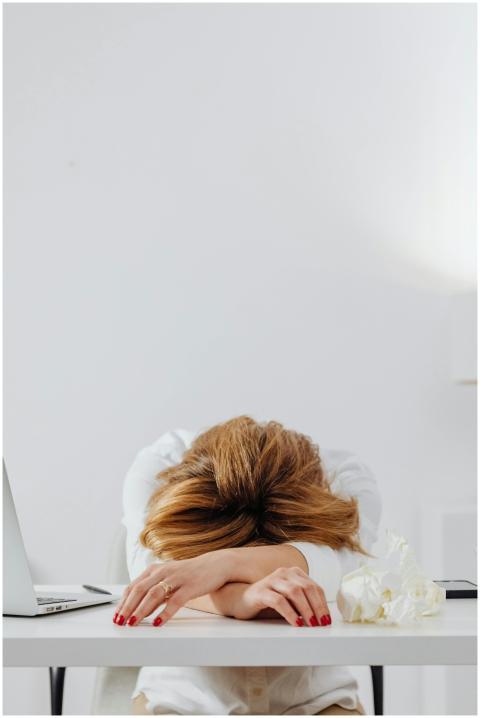 A tired woman with red nails resting her head on a