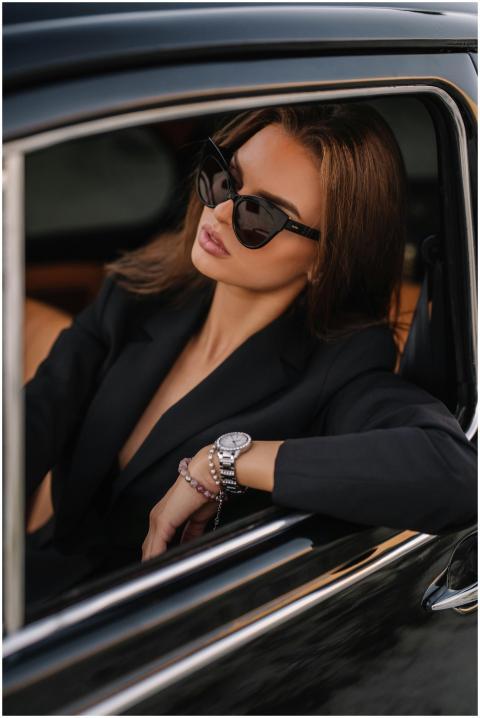 Elegant woman wearing sunglasses, seated in a luxu