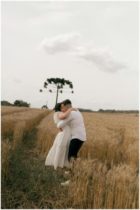 A couple embraces in a golden wheat field under a
