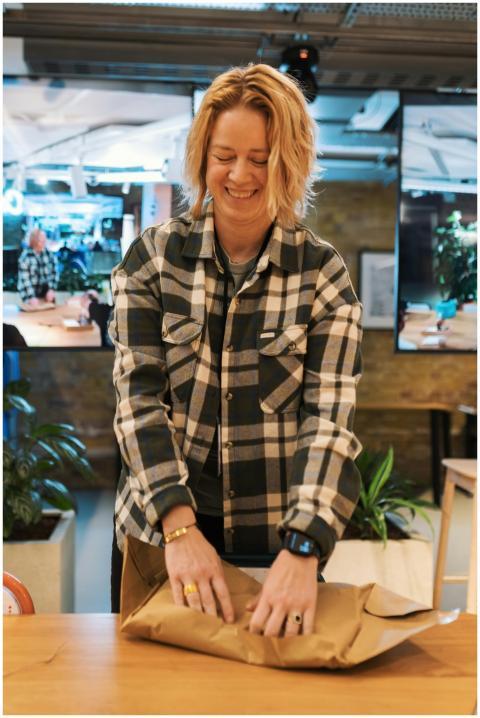 Smiling woman in a plaid shirt wrapping a package